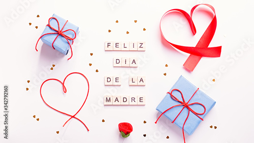 Fotografie Happy Mother's Day greeting card with red hearts, blue gift boxes and golden confetti on pastel table top, overhead shot