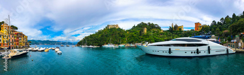 Wide panoramic view of Portofino, one of the world's most beautiful seaside towns on the Italian Riviera. Mediterranean landscape of yacht-filled harbor. ITALY - June, 2018.