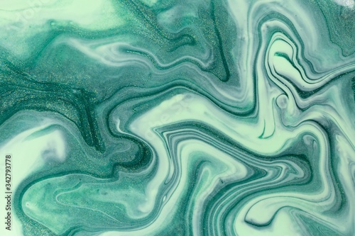 Abstract background of mixed shades of green nail polish with a pastel marble pattern. Liquid colorful background paint creative pastel cold green hue with shimmer