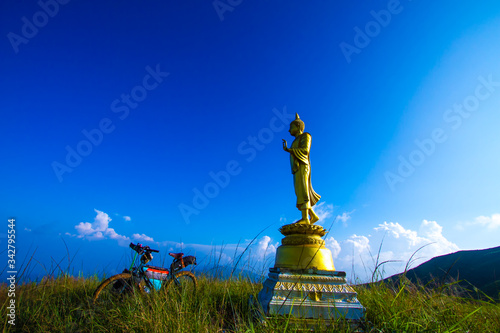 golden buddha statue with bicycle in blue sky