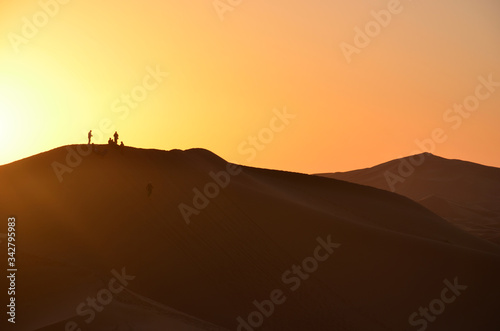 A Sunset View with Tourists Silhouettes on Sahara s Dunes