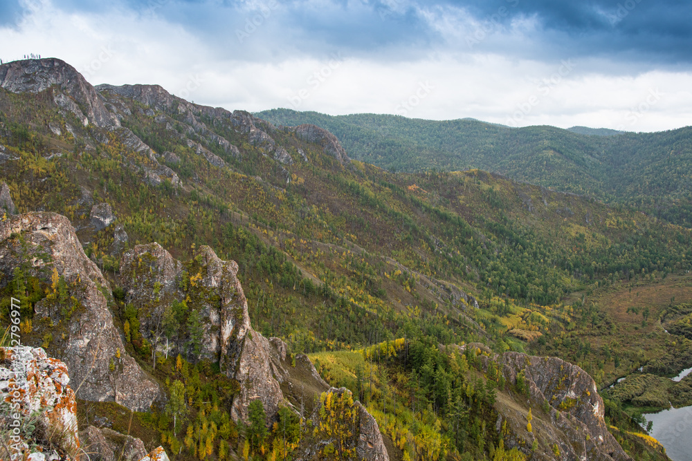 onset of golden autumn in mountain valley, yellow trees and foliage in forest on hills