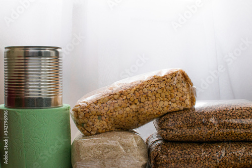 Food supplies during quarantine and self-isolation. Donation. Sugar, buckwheat, canned food, toilet paper, medical face mask, antiseptic for hands and other surfaces, top view, space for text.