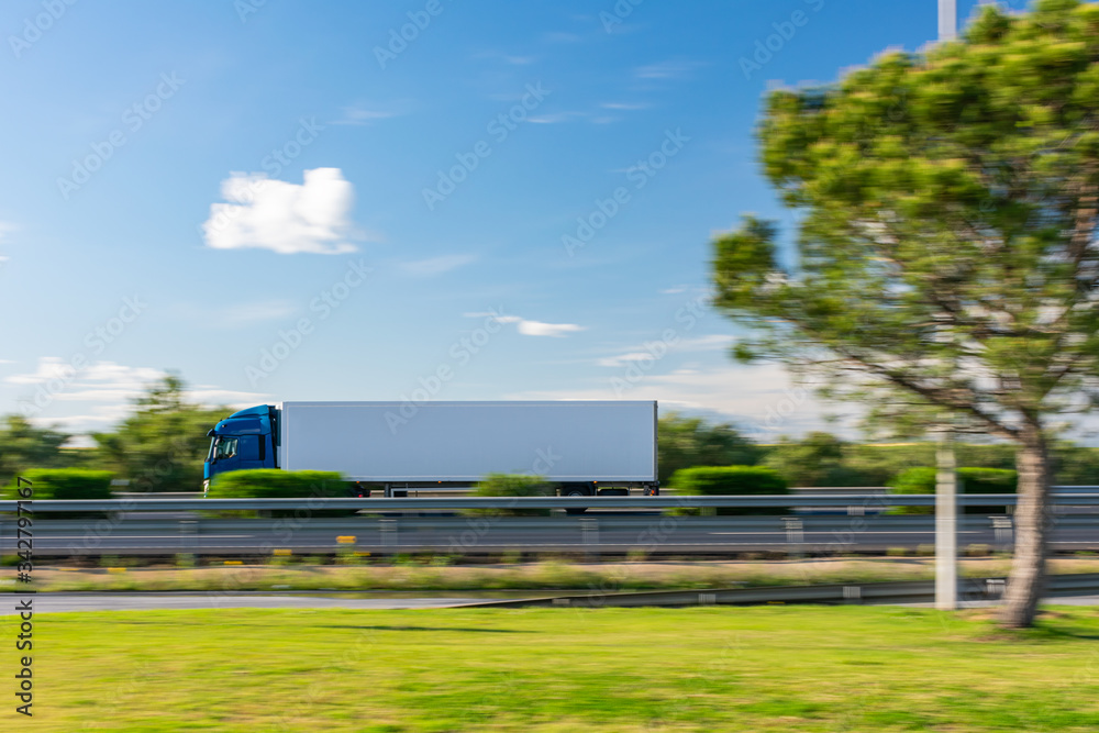 Truck with refrigerated semi-trailer driving on the highway with a blue sky with some clouds