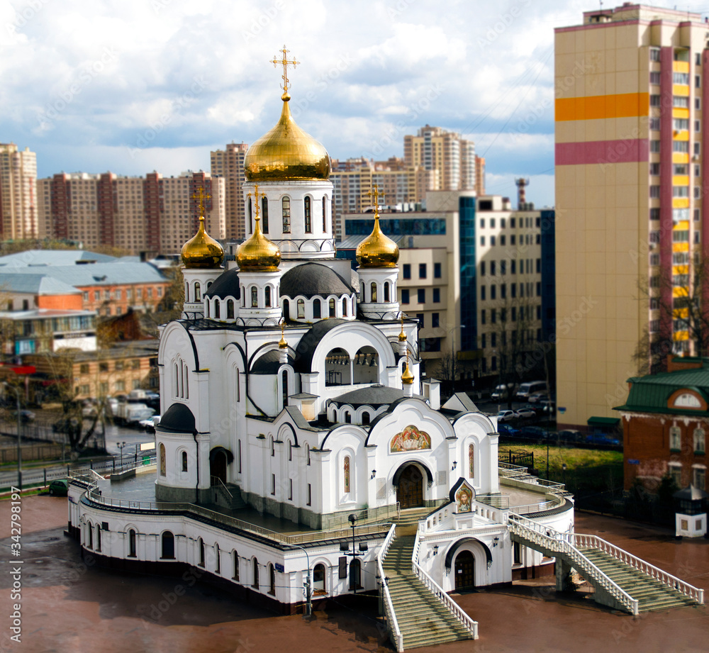 Obraz premium Beautiful white Christian Church with Golden domes on the background of the city landscape.