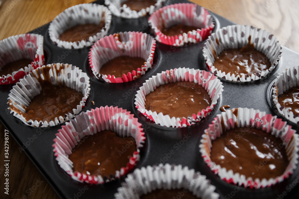 A muffin baking dish in which there are paper inserts with chocolate dough inside. Homemade cakes for children and adults
A muffin baking dish in which there are paper inserts with chocolate dough inside. Homemade cakes for children and adults