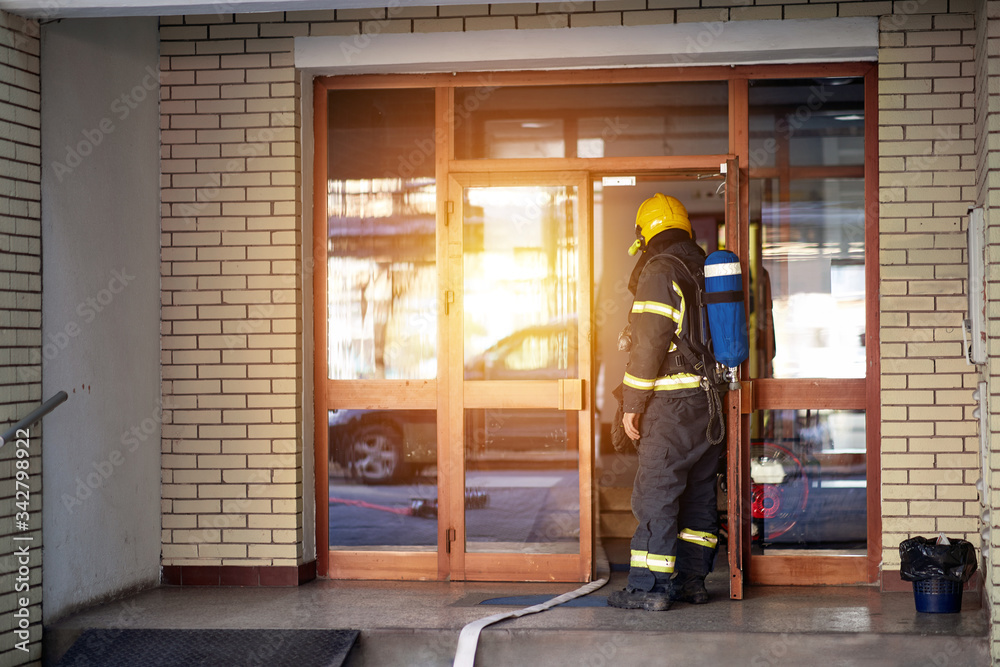Fireman on the job.Fireman in uniform at domestic fire in an apartment building. Fireman on the job.Fireman in uniform at domestic fire in an apartment building.