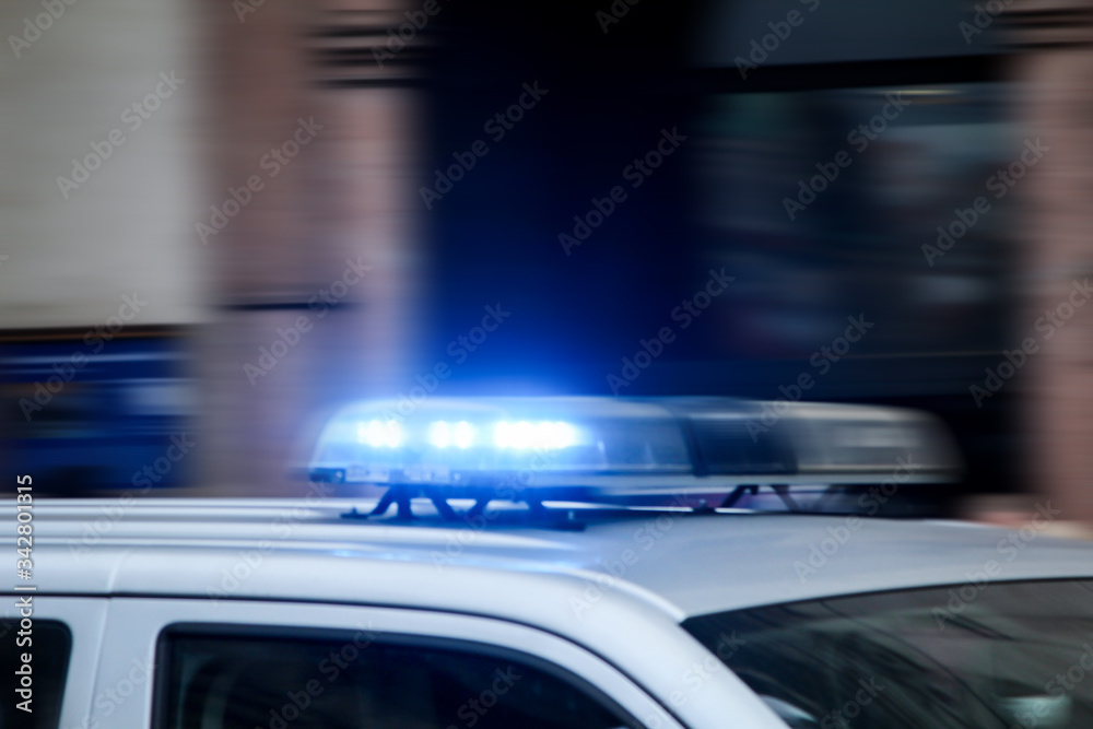 Ein Polizeiauto mit Blaulicht fährt rasant vorbei. Ein Polizeiauto mit Blaulicht fährt rasant vorbei.