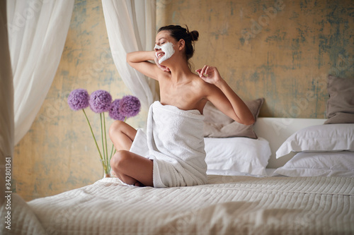 woman with facial mask at morning in bed enjoying and stretching photo