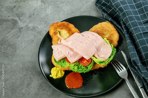 Hot navajo bread, taco with lettuce, tomatoes, ham and sauce on the black plate. Traditional indian recipe navajo bread of yeast-free dough.