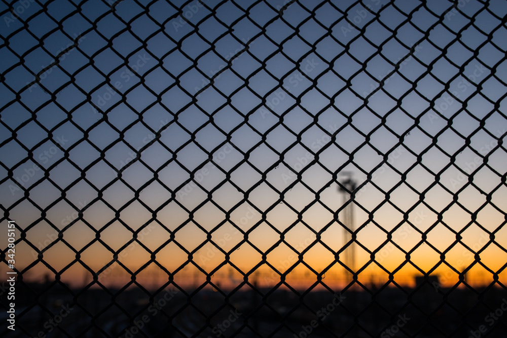 sunset and already twilight are close, an iron grating through which you can see the sky sunset and already twilight are close, an iron grating through which you can see the sky