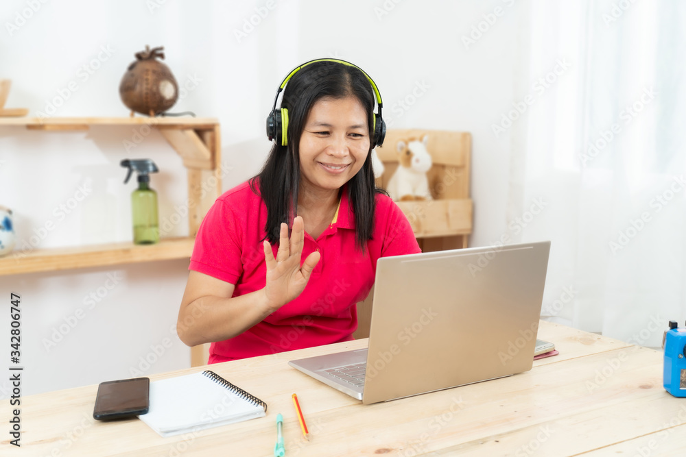 A happy, casual woman working on a laptop sitting at a desk in the house A happy, casual woman working on a laptop sitting at a desk in the house
