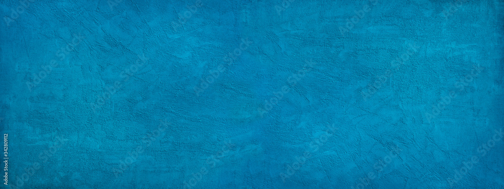 Beautiful abstract blue background. Texture of decorative plaster on a concrete wall. Bright blue banner with a rough grainy plastered surface.