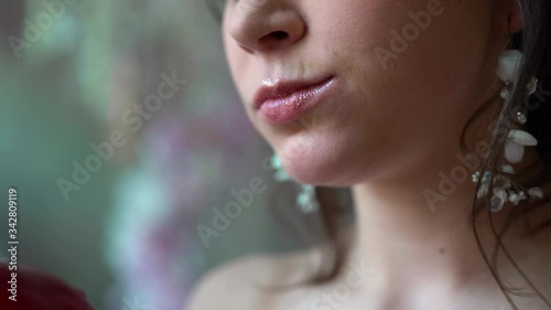 the girl s lips bite and eat a red apple. The woman s face is close-up, only her mouth. The jaw opens and eats food. The teeth bite the fruit. The lips are painted with lipstick.