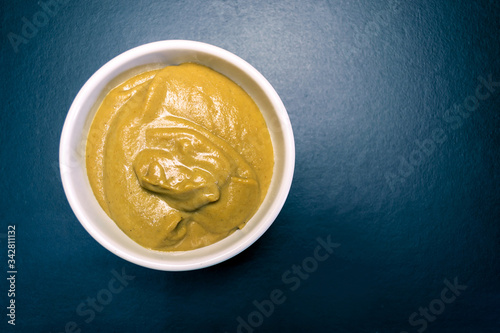 Mustard sauce in a white plate on a black background