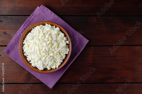 Cottage cheese on wooden boards. Fresh cottage cheese in a ceramic bowl. Clay plate with soft cheese on a linen napkin. Top view. Copy space