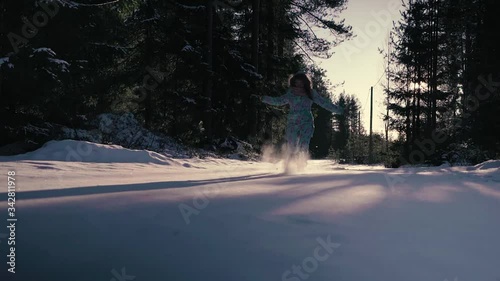 the girl runs joyfully through the woods in a slow motion. behind the trees, the woman is dressed in a blue jumpsuit, she runs along the path