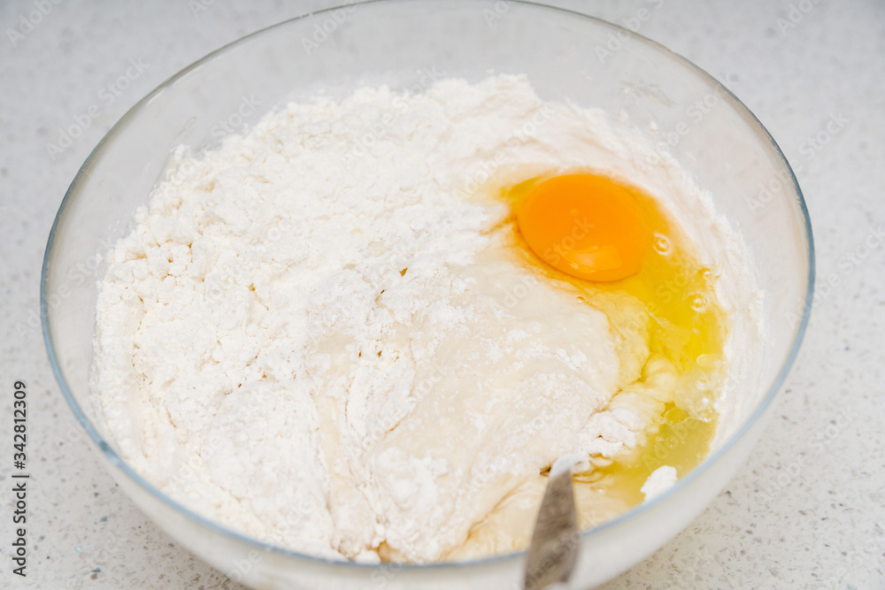 Preparation of the yeast dough. Dough with the egg`s yolk and flavour in the glass bowl is ready to be stirred. Preparation of the yeast dough. Dough with the egg`s yolk and flavour in the glass bowl is ready to be stirred.