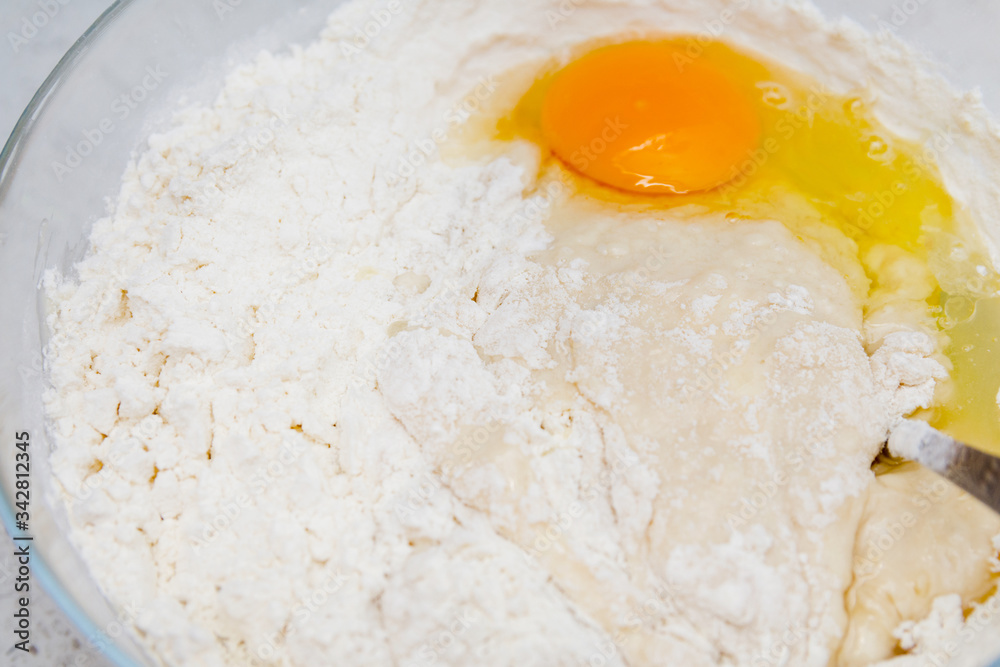 Preparation of the yeast dough. Dough with the egg`s yolk and flavour in the glass bowl is ready to be stirred. Preparation of the yeast dough. Dough with the egg`s yolk and flavour in the glass bowl is ready to be stirred.