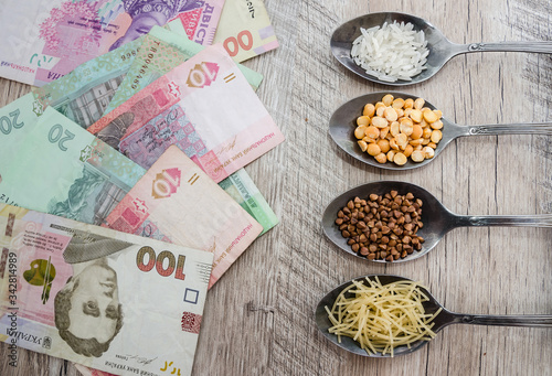 composition with various types of legumes and cereals in spoons on a wooden table. Organic grains and dollars. The concept of economic crisis and rising prices. Rice, buckwheat, pasta and hryvnia.