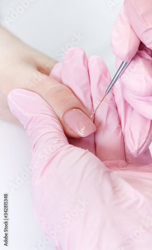 Woman in nail salon receiving manicure by beautician. Manicure process in beauty salon  close up. Close up of a woman hand with pink nail polish after the manicure.