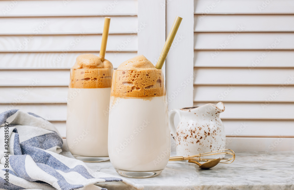 Iced frothy Dalgona Coffee, a trendy fluffy creamy whipped coffee. Korean drink latte espresso with coffee foam. made of instant coffee, sugar, hot water and milk.