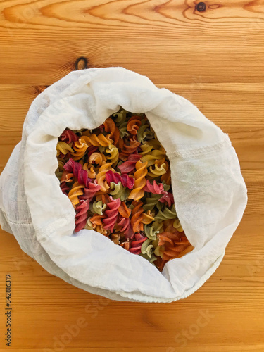 Zero waste shopping. Organic colorful pasta in reusable bag close up. Groceries in reusable textile bags on wooden table. Plastic free delivery from bulk store.  Ban plastic