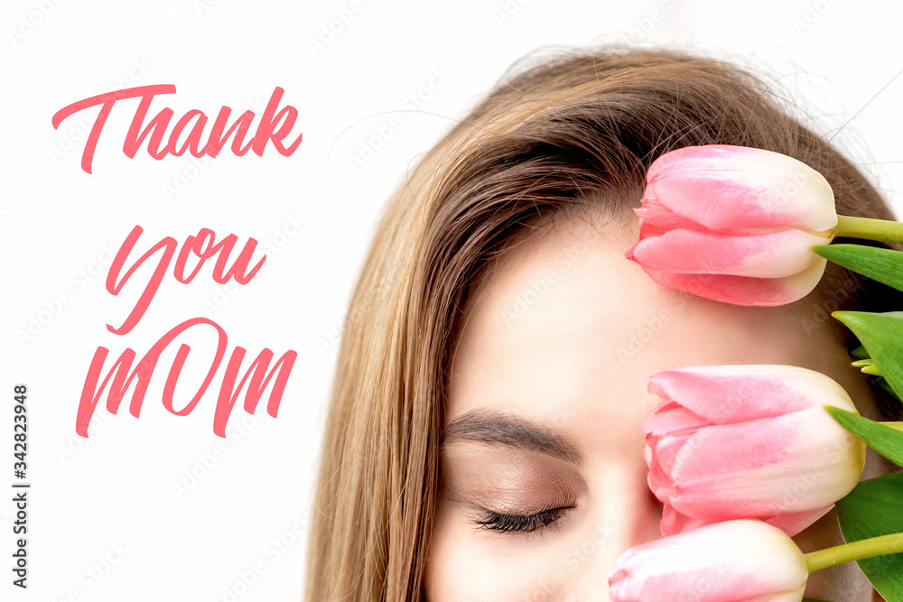 Smiling young woman with pink tulips, sign text Thank You Mom on white background. Mother's day celebration card.