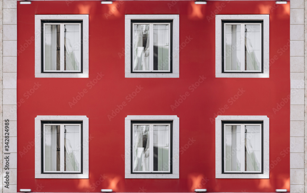 Six vintage windows on a bright red wall. Exterior facade of red historical house with apartments in Lisbon, Portugal