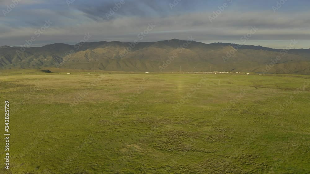 Flying over a green prairie high above the Aqua Fria National Monument in Arizona with interstate traffic and mountains in the distance.