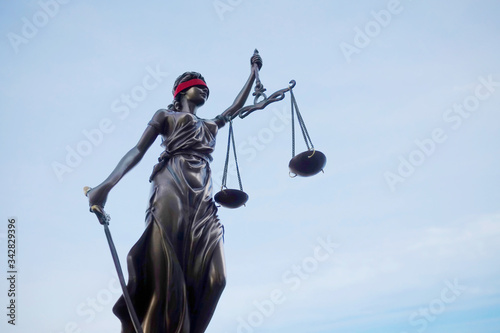 Justitia Lady justice statue with blindfold against blue sky photo