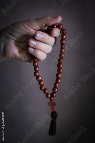 womans hand with wooden rosary or prayer beads