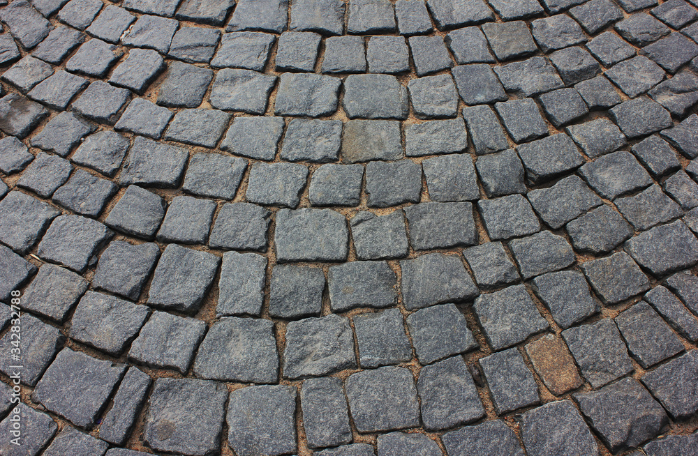 Cobblestone pavement pattern on city street. Old town stone pavement, empty cobbled city road with no people. Paved cobblestone street close up view