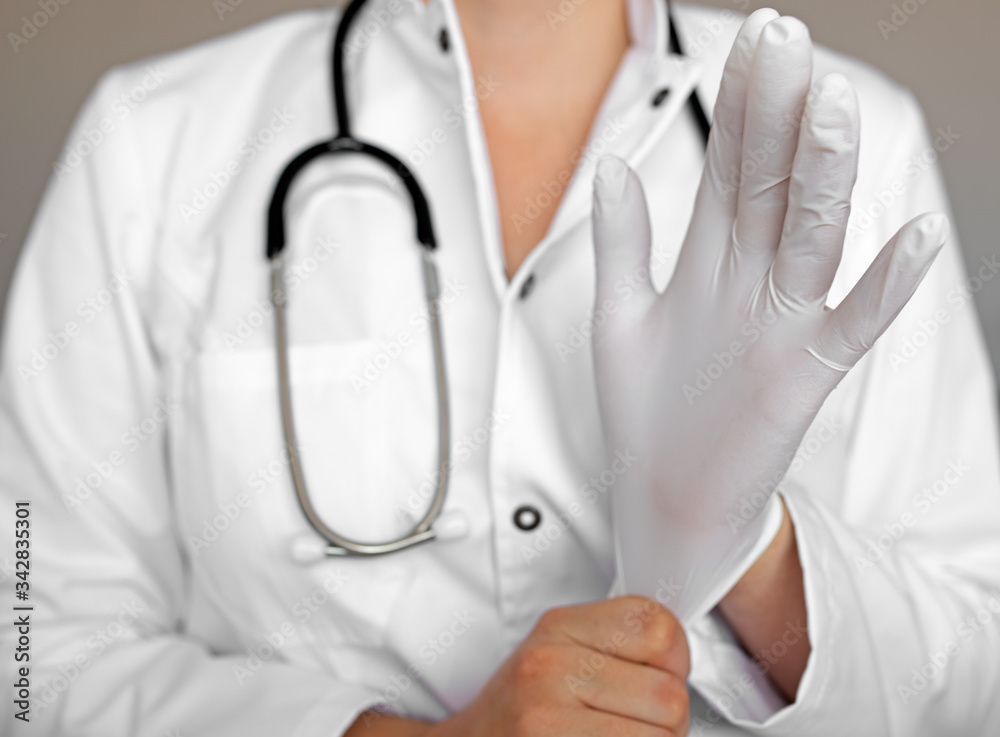 Young female doctor putting on latex gloves isolated on white Young female doctor putting on latex gloves isolated on white
