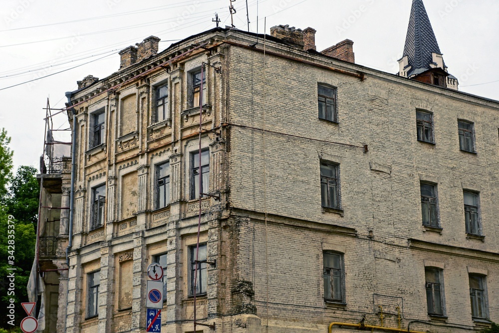 Fototapeta premium facade of a large brown old brick house with a row of windows against a gray sky