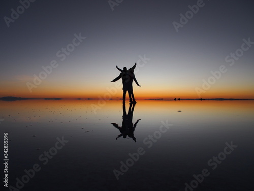 Couple hand by hand on the sunrise, Uyuni Salt Flat, Salar de Uyuni, Bolivia. Copy space for text