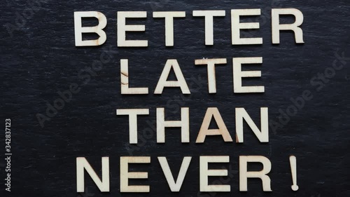 Stop motion of wooden letters writing BETTER LATE THAN NETHER on slate background