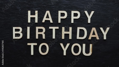 Stop motion of wooden letters writing HAPPY BIRTHDAY on slate background