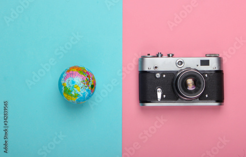 Tourism and travel concept. Globe, camera on pink blue pastel background. Top view. Flat lay