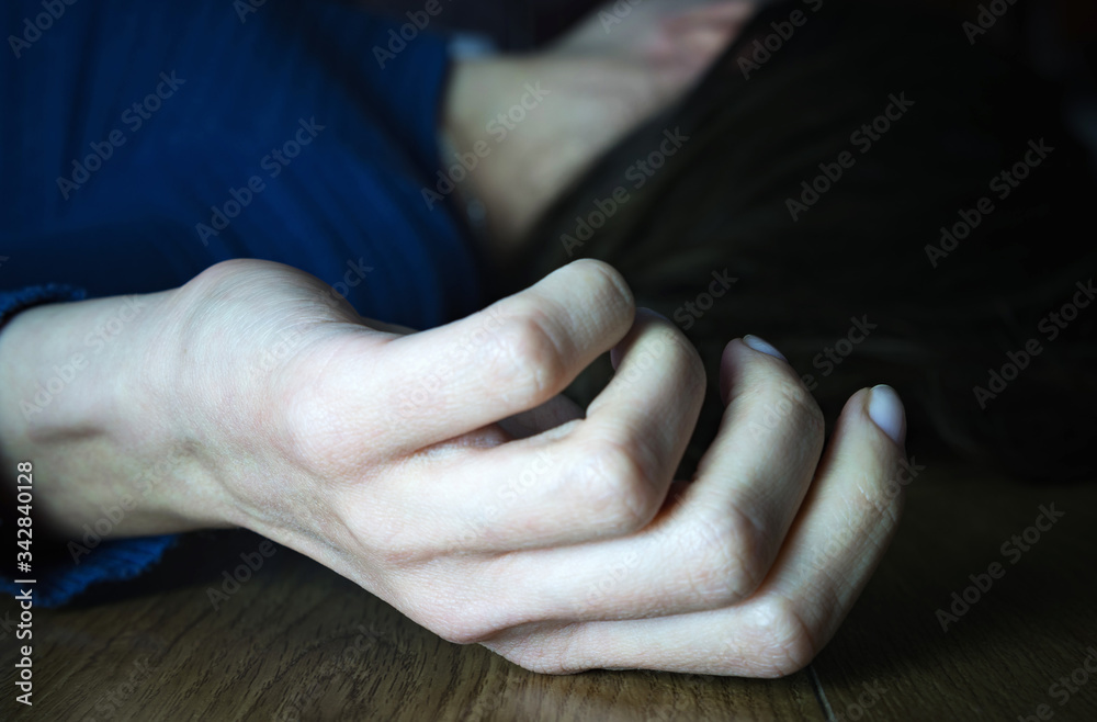 Hand of a dead or unconscious woman lying on the floor in the dark. Crime scene, violence in family, symbolic image. 