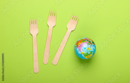 Eco still life. Plastic free concept. Globe with wooden forks on a green background. Top view