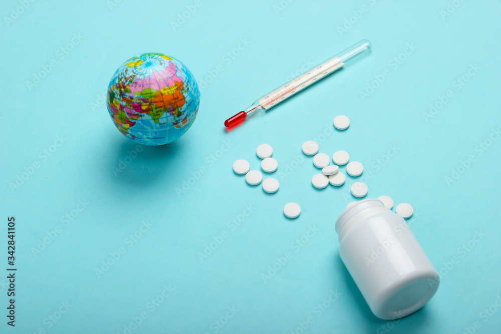 Global pandemic still life. Globe, thermometer with bottle of pills on blue background. Coronovirus outbreak Global pandemic still life. Globe, thermometer with bottle of pills on blue background. Coronovirus outbreak