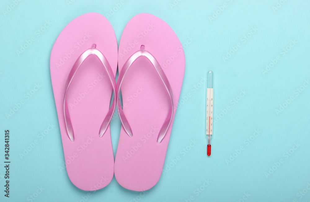 Flat lay summer background. Beach vacation. Flip flops and thermometer on blue background. Top view