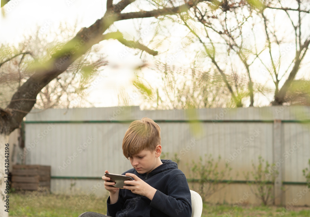 Fototapeta premium Caucasian blond boy plays on smartphone