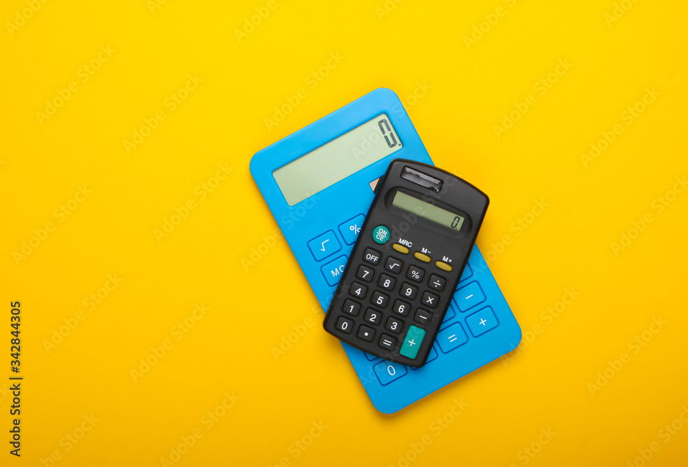 Two calculators on yellow background. Top view. Two calculators on yellow background. Top view.