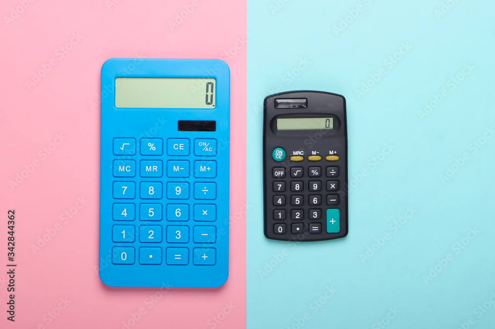 Two calculators on blue pink pastel background. Top view. Two calculators on blue pink pastel background. Top view.