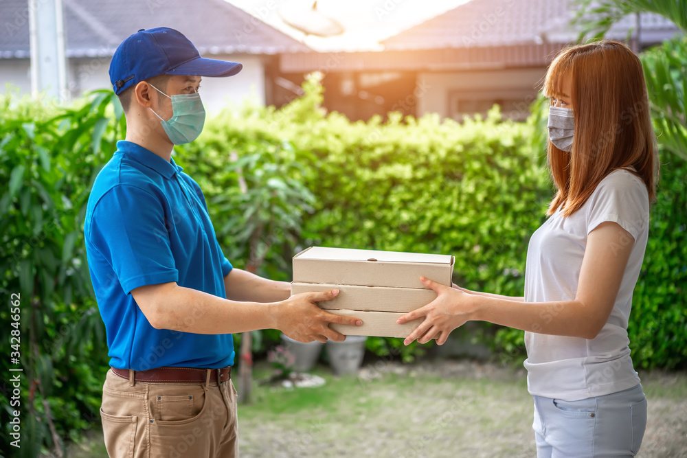 Asian deliveryman is delivering a package to a female customer in front her house. For her to sign to receive the product After she ordered online during the outbreak of coronavirus or Covid-19 virus. Asian deliveryman is delivering a package to a female customer in front her house. For her to sign to receive the product After she ordered online during the outbreak of coronavirus or Covid-19 virus.