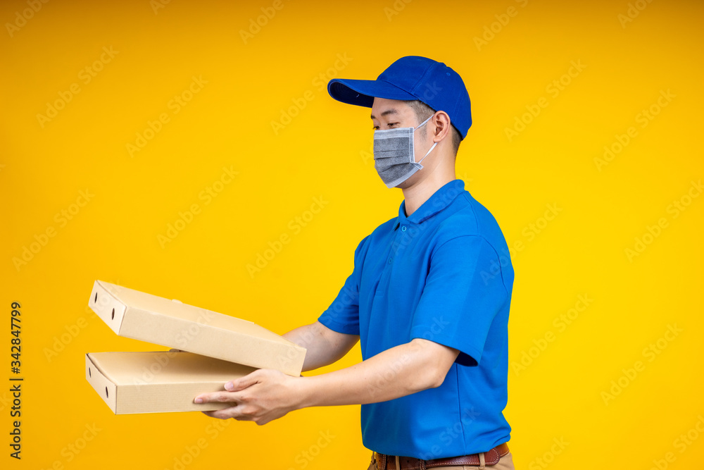 Young Asian delivery man holding food or pizza box and showing application on mobile over yellow isolate background. Work from home and delivery concept. Young Asian delivery man holding food or pizza box and showing application on mobile over yellow isolate background. Work from home and delivery concept.