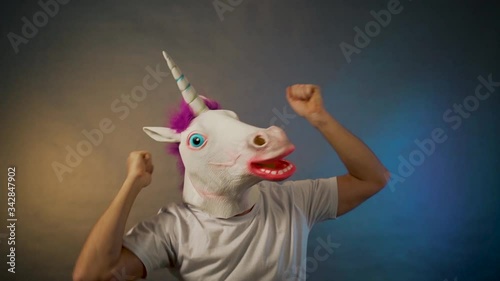 the man dancing in the unicorn mask on gray background
