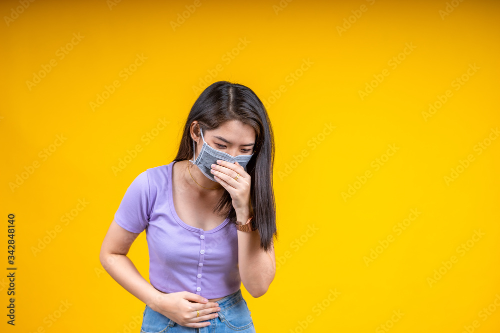 Young Asian woman wearing mask points sneeze or cough over yellow background. Corona virus or covid-19 concept. Young Asian woman wearing mask points sneeze or cough over yellow background. Corona virus or covid-19 concept.